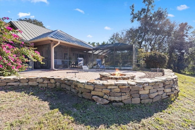 back of property featuring a fire pit, a sunroom, a lanai, and a patio