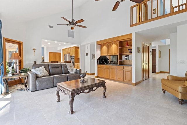 living room featuring built in shelves, ceiling fan, and high vaulted ceiling