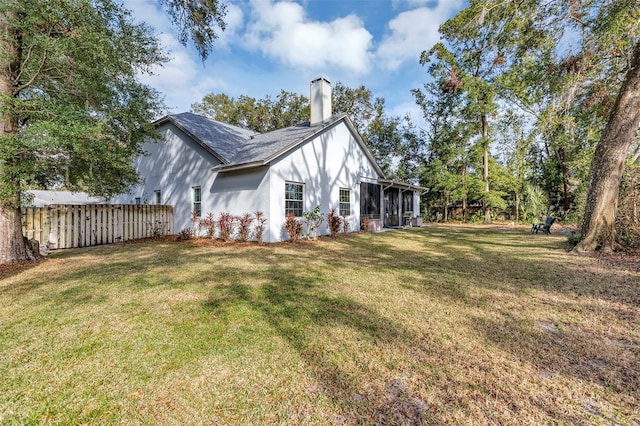 view of side of home with a sunroom and a yard