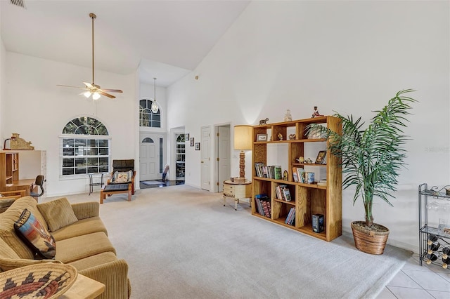 carpeted living room with ceiling fan and a towering ceiling