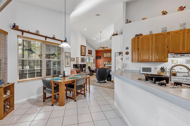 kitchen with light tile patterned floors, high vaulted ceiling, hanging light fixtures, and ceiling fan