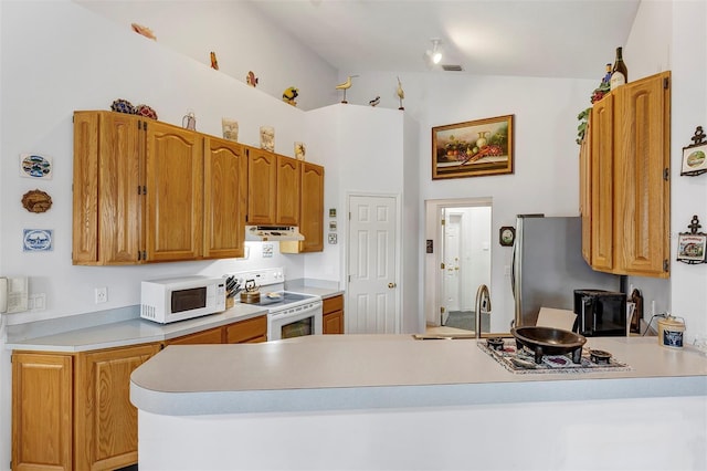 kitchen with sink, white appliances, kitchen peninsula, and vaulted ceiling