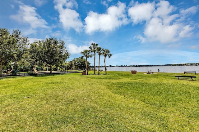 surrounding community featuring a playground, a yard, and a water view