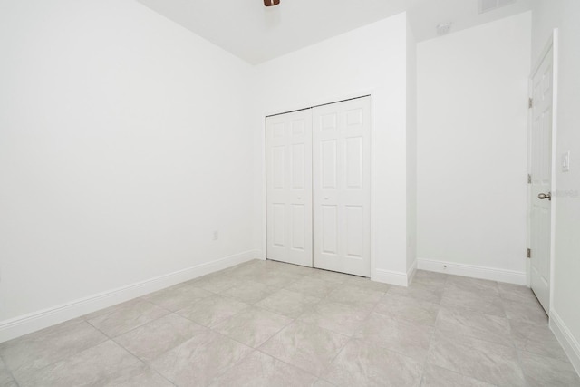 unfurnished bedroom featuring ceiling fan, a closet, and light tile patterned floors