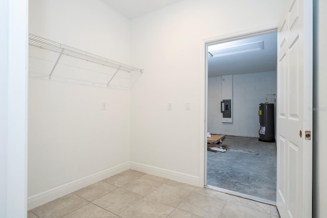 clothes washing area with electric panel, water heater, and light tile patterned floors