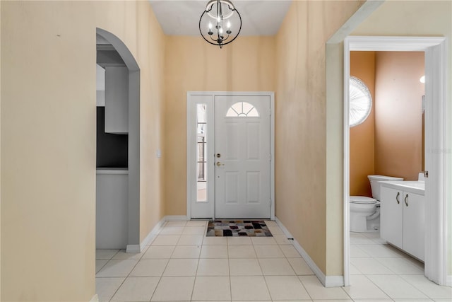 tiled entryway with a chandelier