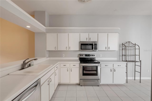 kitchen with sink, light tile patterned floors, white cabinets, and appliances with stainless steel finishes