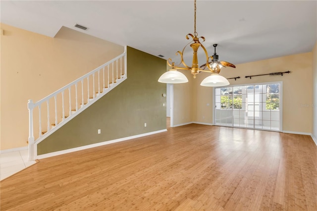 unfurnished living room with an inviting chandelier and wood-type flooring