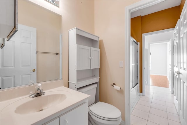 full bathroom with vanity, bath / shower combo with glass door, tile patterned floors, and toilet