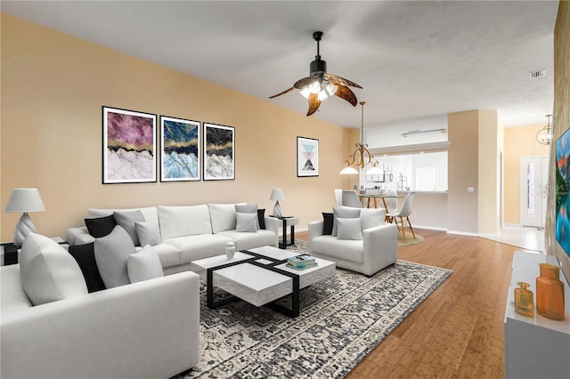 living room with wood-type flooring and ceiling fan with notable chandelier