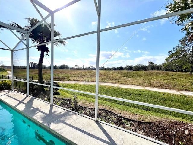 view of swimming pool featuring a lanai, a lawn, and a rural view