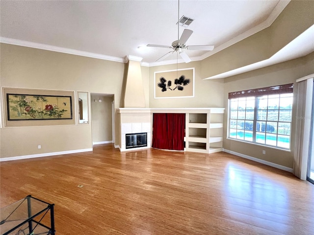 unfurnished living room featuring hardwood / wood-style floors, ceiling fan, crown molding, and a fireplace