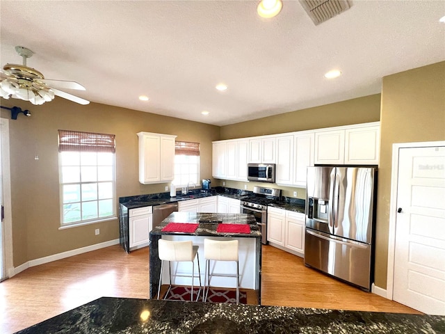 kitchen featuring stainless steel appliances, ceiling fan, sink, white cabinets, and light hardwood / wood-style floors