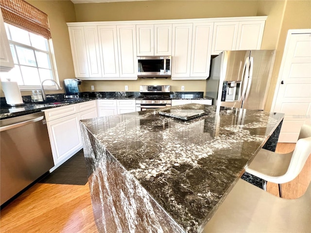 kitchen with sink, white cabinetry, stainless steel appliances, and dark stone counters