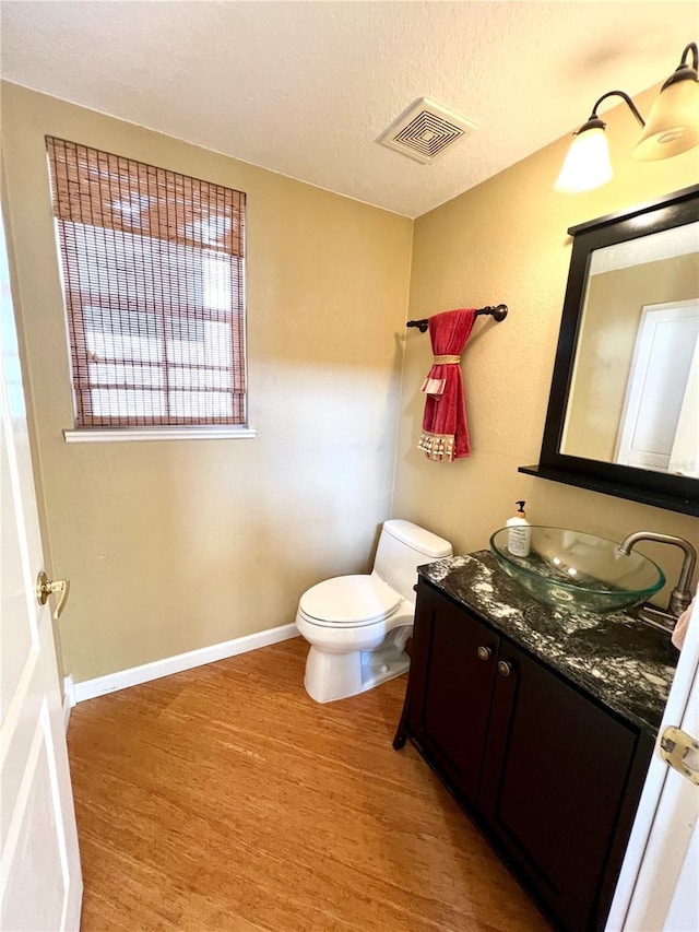 bathroom featuring wood-type flooring, vanity, a textured ceiling, and toilet