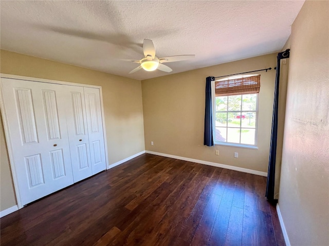 unfurnished bedroom with a textured ceiling, ceiling fan, dark wood-type flooring, and a closet