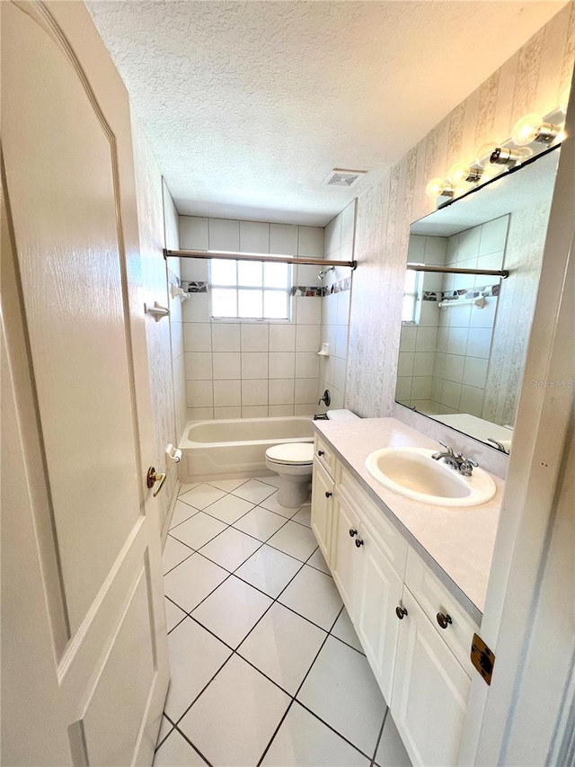 full bathroom with a textured ceiling, vanity, tile patterned flooring, toilet, and tiled shower / bath