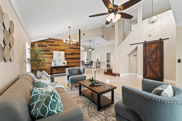 living room featuring wood walls, ceiling fan with notable chandelier, crown molding, a barn door, and light tile patterned floors