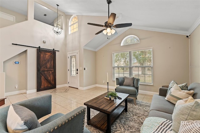 living room with a towering ceiling, ceiling fan, crown molding, light tile patterned floors, and a barn door