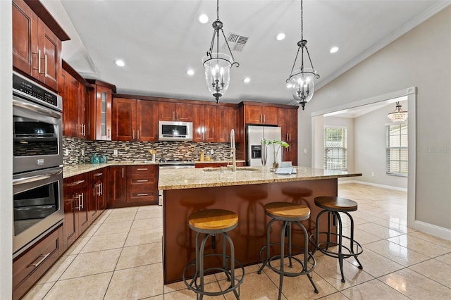 kitchen with appliances with stainless steel finishes, a kitchen island with sink, sink, a chandelier, and lofted ceiling