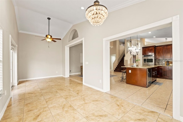 kitchen featuring lofted ceiling, backsplash, a kitchen breakfast bar, ceiling fan with notable chandelier, and a kitchen island