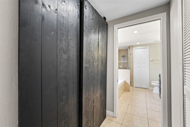 bathroom with tile patterned floors, toilet, and tiled bath