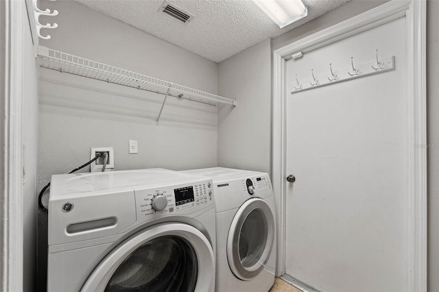 clothes washing area with a textured ceiling and independent washer and dryer