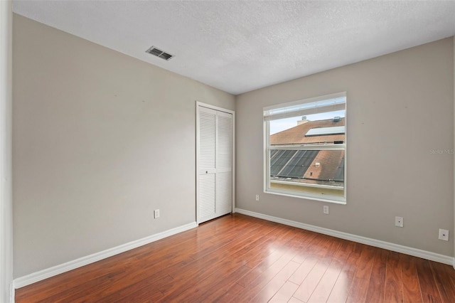 spare room featuring a textured ceiling and hardwood / wood-style flooring