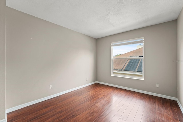 empty room featuring dark wood-type flooring and a textured ceiling