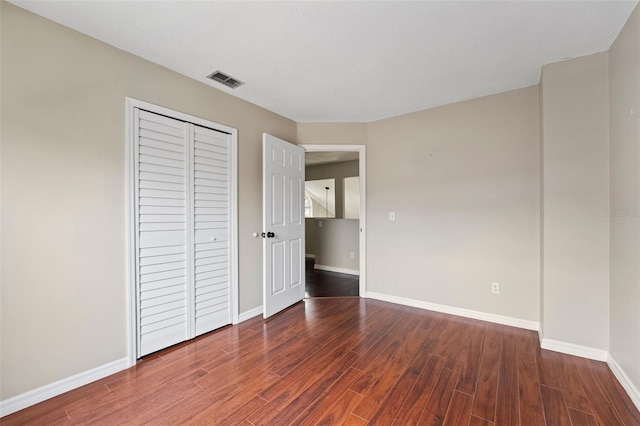 unfurnished bedroom featuring a closet and dark hardwood / wood-style flooring