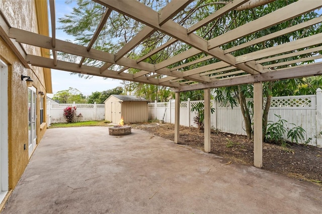 view of patio with a pergola, a shed, and an outdoor fire pit