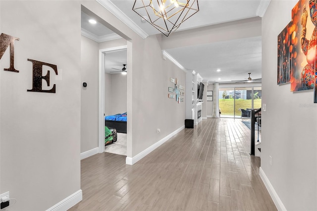 hallway featuring crown molding, light hardwood / wood-style flooring, and a notable chandelier