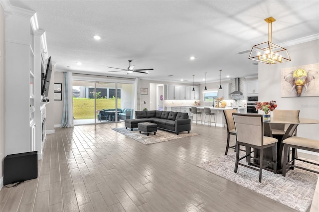 living room with crown molding and ceiling fan with notable chandelier