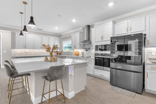 kitchen featuring white cabinets, wall chimney exhaust hood, stainless steel fridge, and a center island