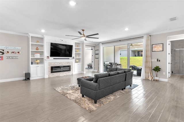 living room with ceiling fan, crown molding, and a fireplace