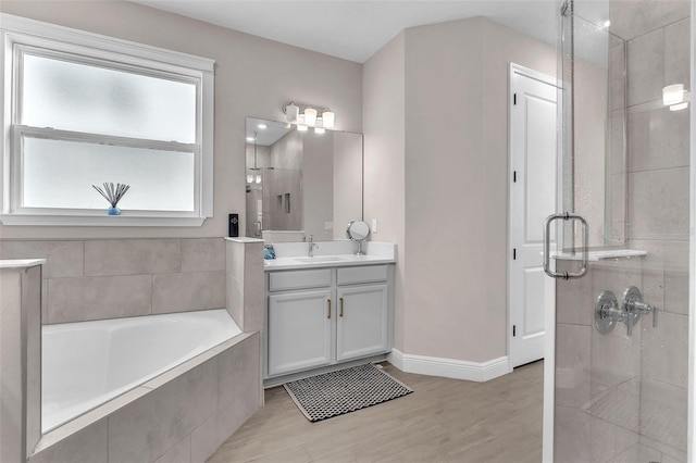 bathroom with plus walk in shower, hardwood / wood-style flooring, and vanity