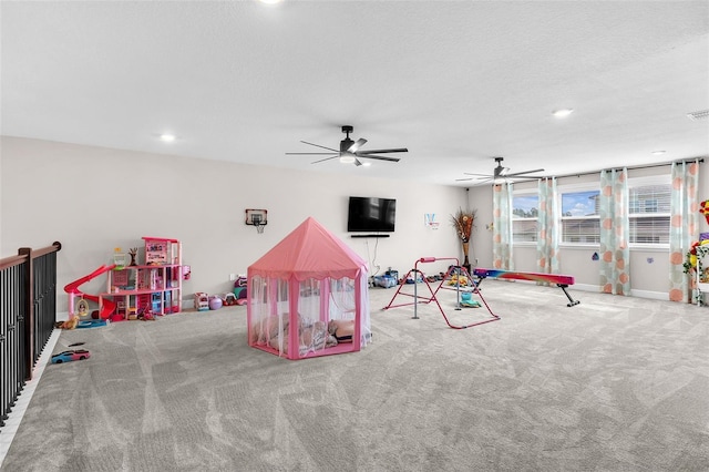 recreation room with a textured ceiling, ceiling fan, and carpet flooring