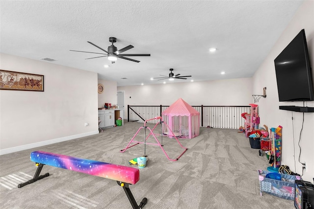 game room featuring ceiling fan, light colored carpet, and a textured ceiling