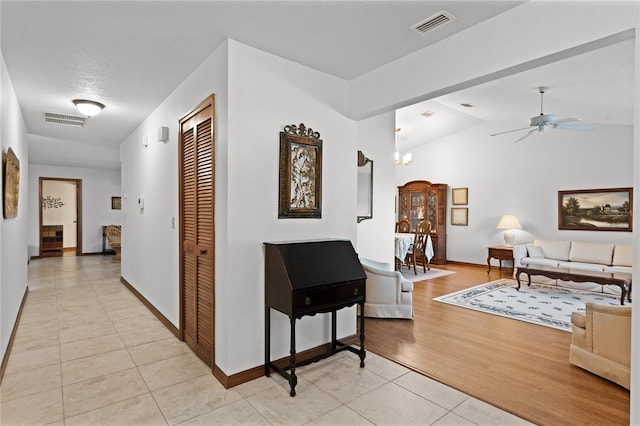 corridor with lofted ceiling, light tile patterned floors, a textured ceiling, and an inviting chandelier