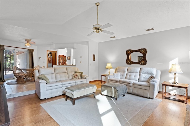 living room with light hardwood / wood-style floors, vaulted ceiling, and ceiling fan