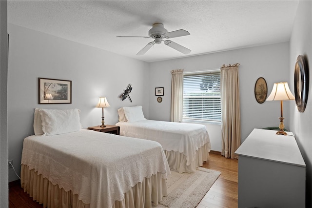 bedroom with a textured ceiling, light hardwood / wood-style floors, and ceiling fan