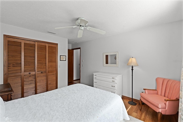 bedroom with hardwood / wood-style flooring, ceiling fan, a textured ceiling, and a closet