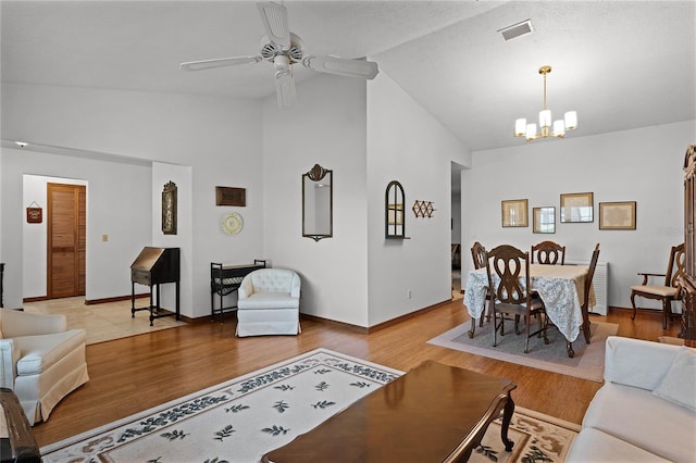 living room featuring wood-type flooring, ceiling fan with notable chandelier, and high vaulted ceiling