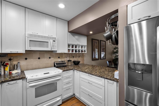 kitchen with dark stone countertops, white appliances, tasteful backsplash, and white cabinets