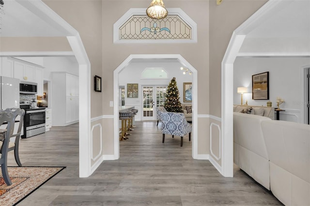 entryway with french doors, a towering ceiling, and light wood-type flooring