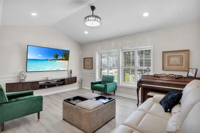 living room featuring light hardwood / wood-style flooring, vaulted ceiling, and a notable chandelier