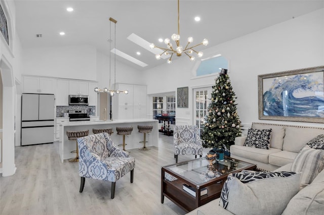 living room with light hardwood / wood-style floors, sink, high vaulted ceiling, and a chandelier