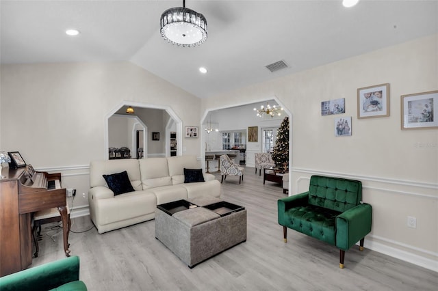 living room featuring light hardwood / wood-style floors, an inviting chandelier, and lofted ceiling