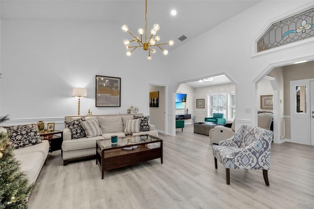 living room with high vaulted ceiling, a notable chandelier, and light wood-type flooring