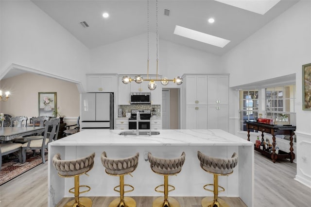 kitchen featuring stainless steel appliances, white cabinetry, a skylight, and sink